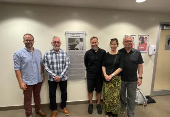 Five folks standing by "Walter Krepski Conditioning Floor" plaque