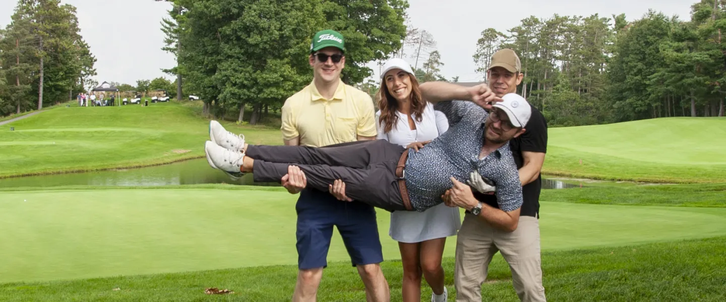 Three golfers lifting another in the air