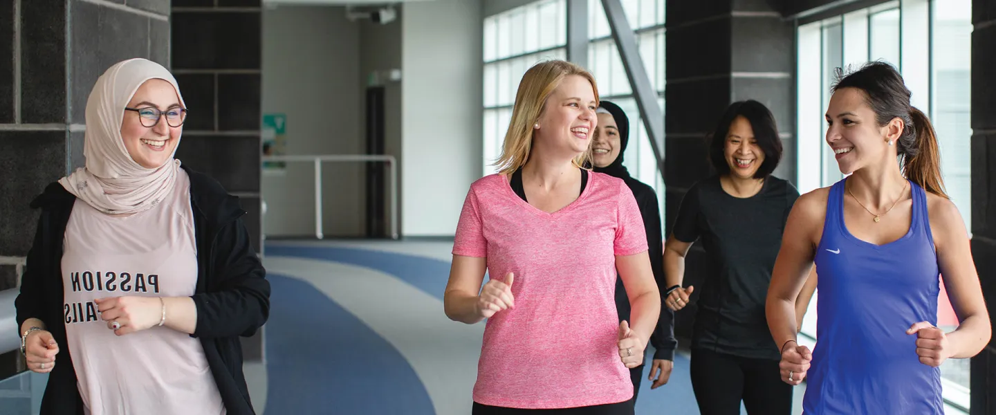 A group of friends walk together on an indoor track.