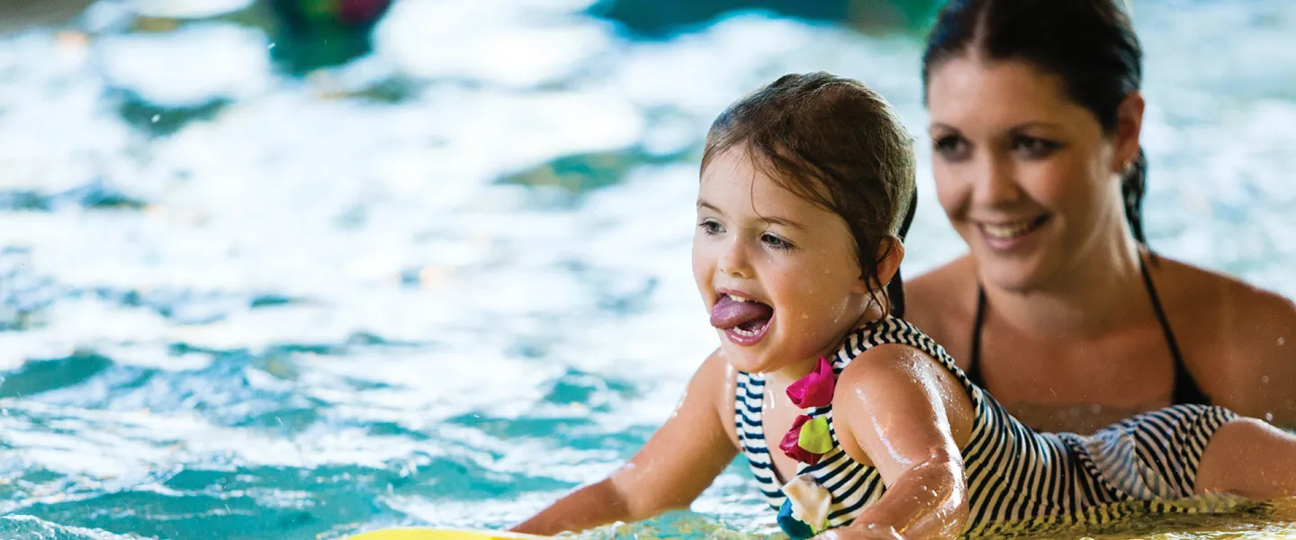 A mother and her daughter swimming in the pool.