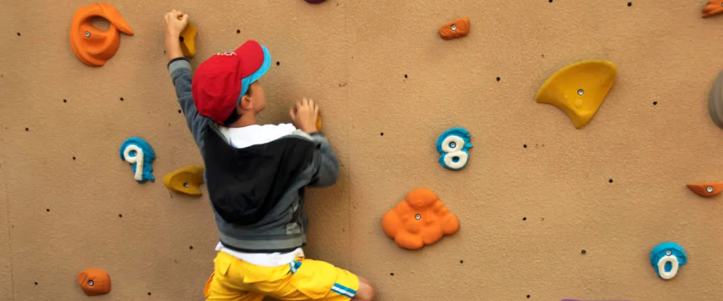 A camper climbs an artificial rock wall.