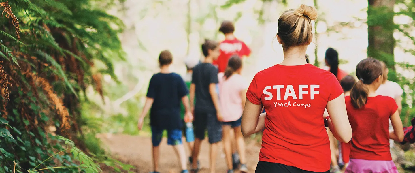 A group of children and camp counsellors walking down an outdoor path