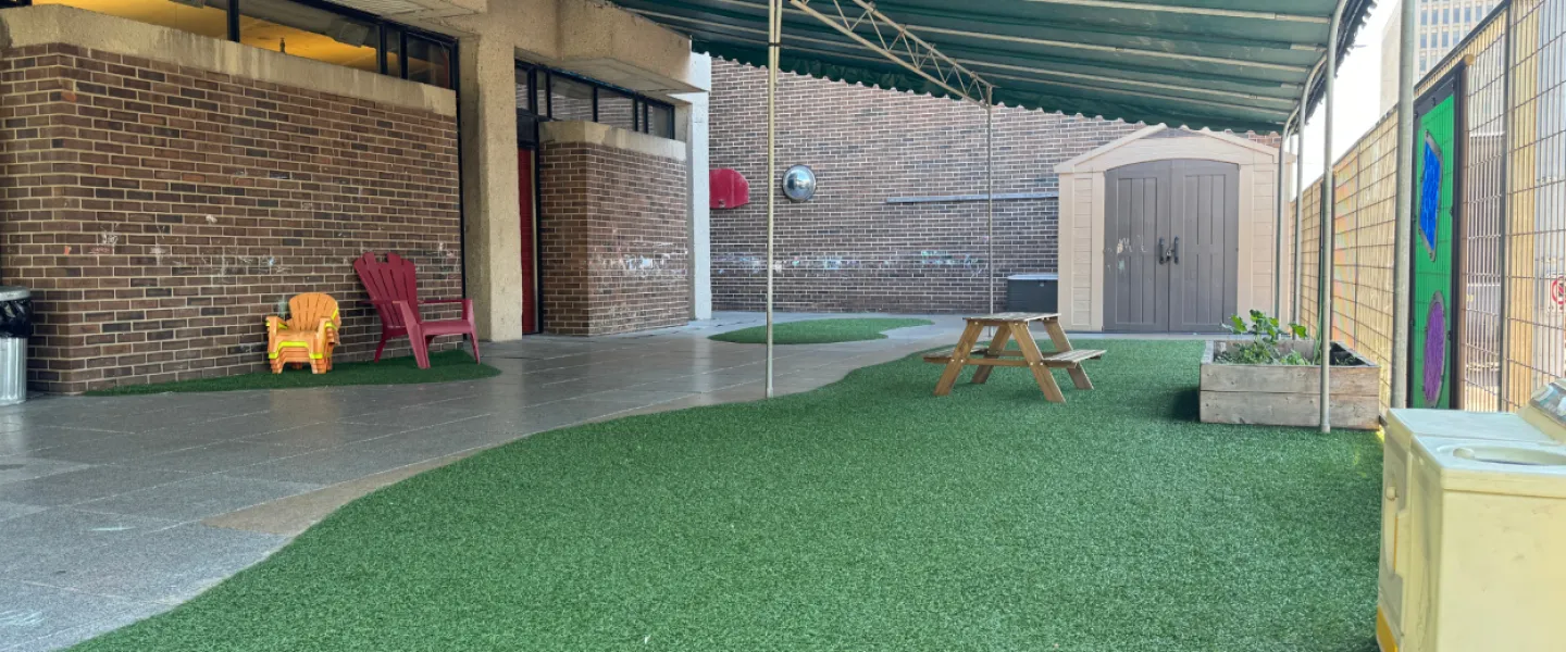 A covered outdoor play area with chairs and a picnic table.