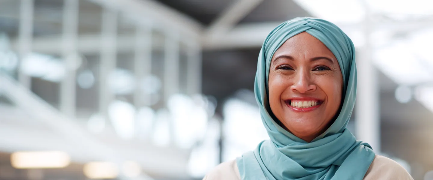 A smiling woman wearing a hijab.