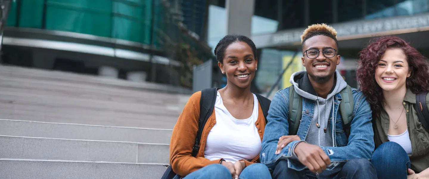 Three diverse youth sit on steps.