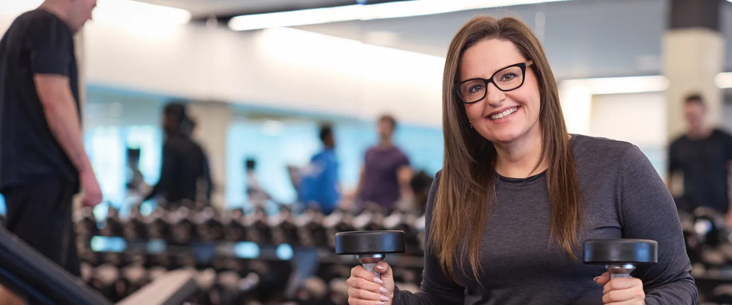 A woman works out with weights in the gym.