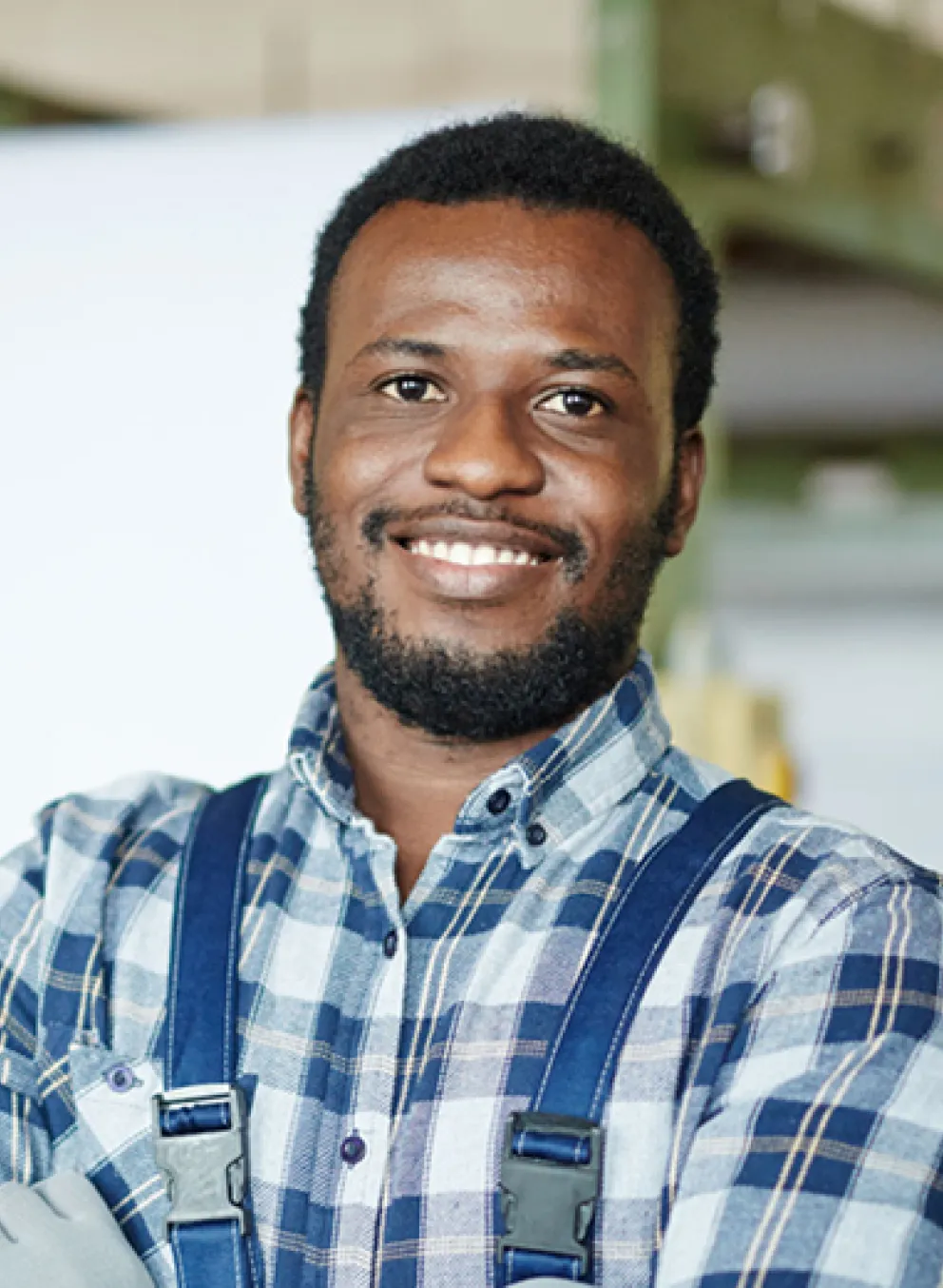 A smiling man with his arms crossed stands in front of machinery.