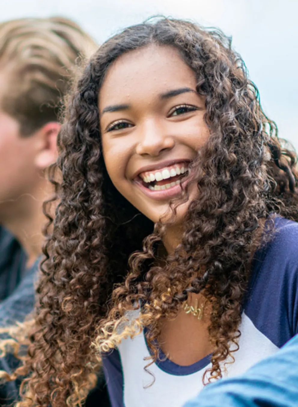 A diverse group of smiling young people sitting together outside.