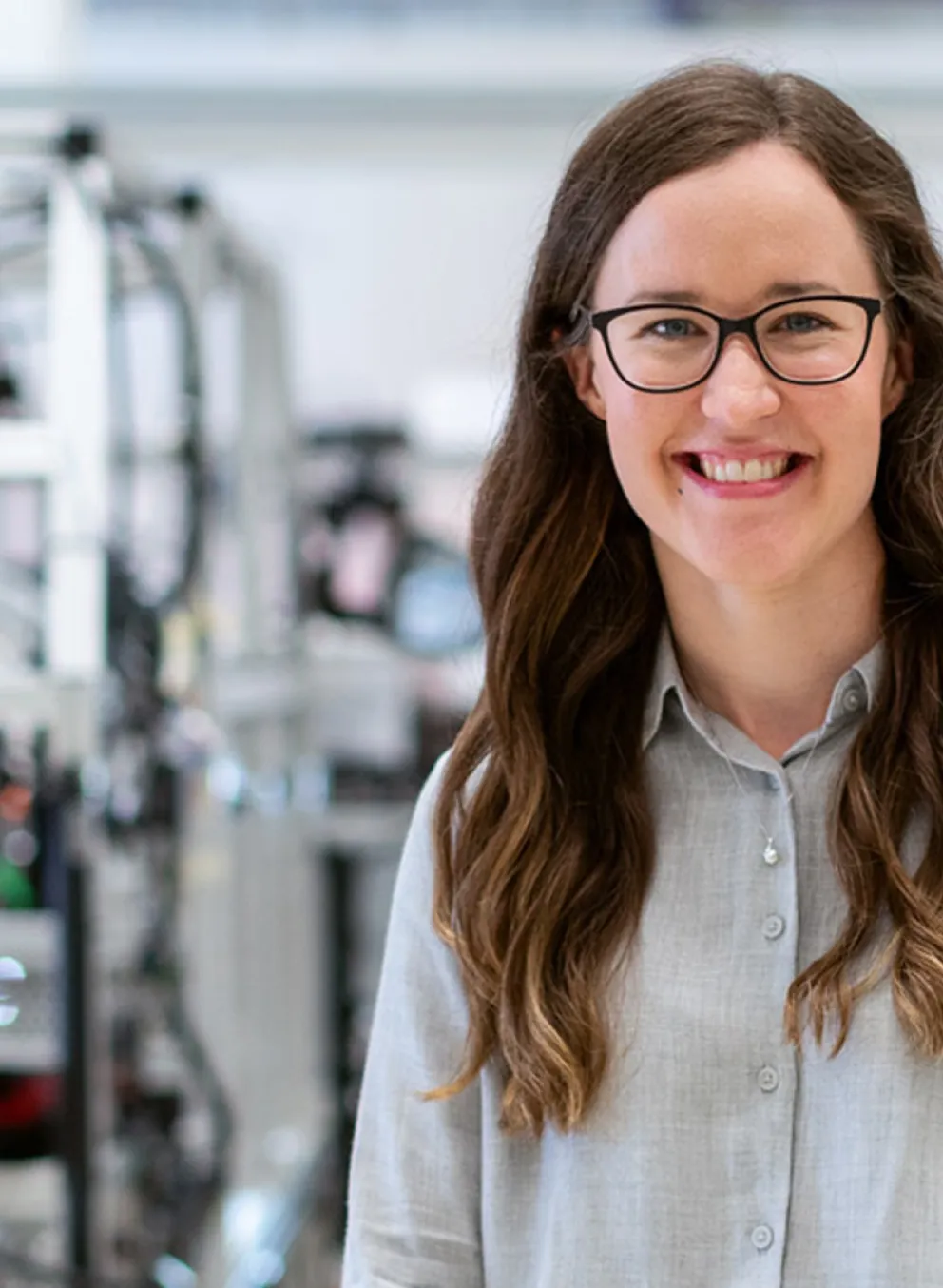 A smiling woman stands in a factory.