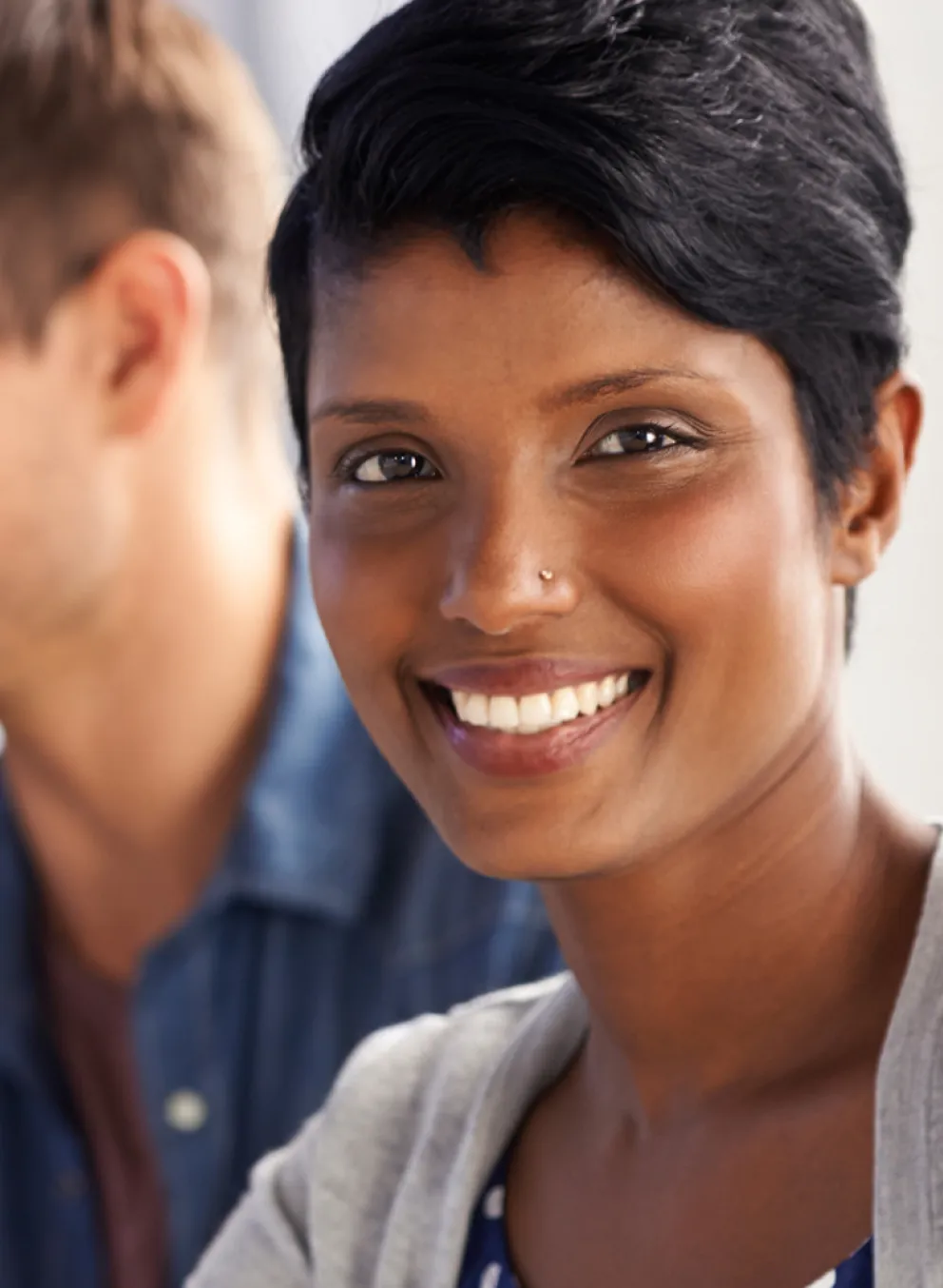 A smiling woman looks directly into the camera.