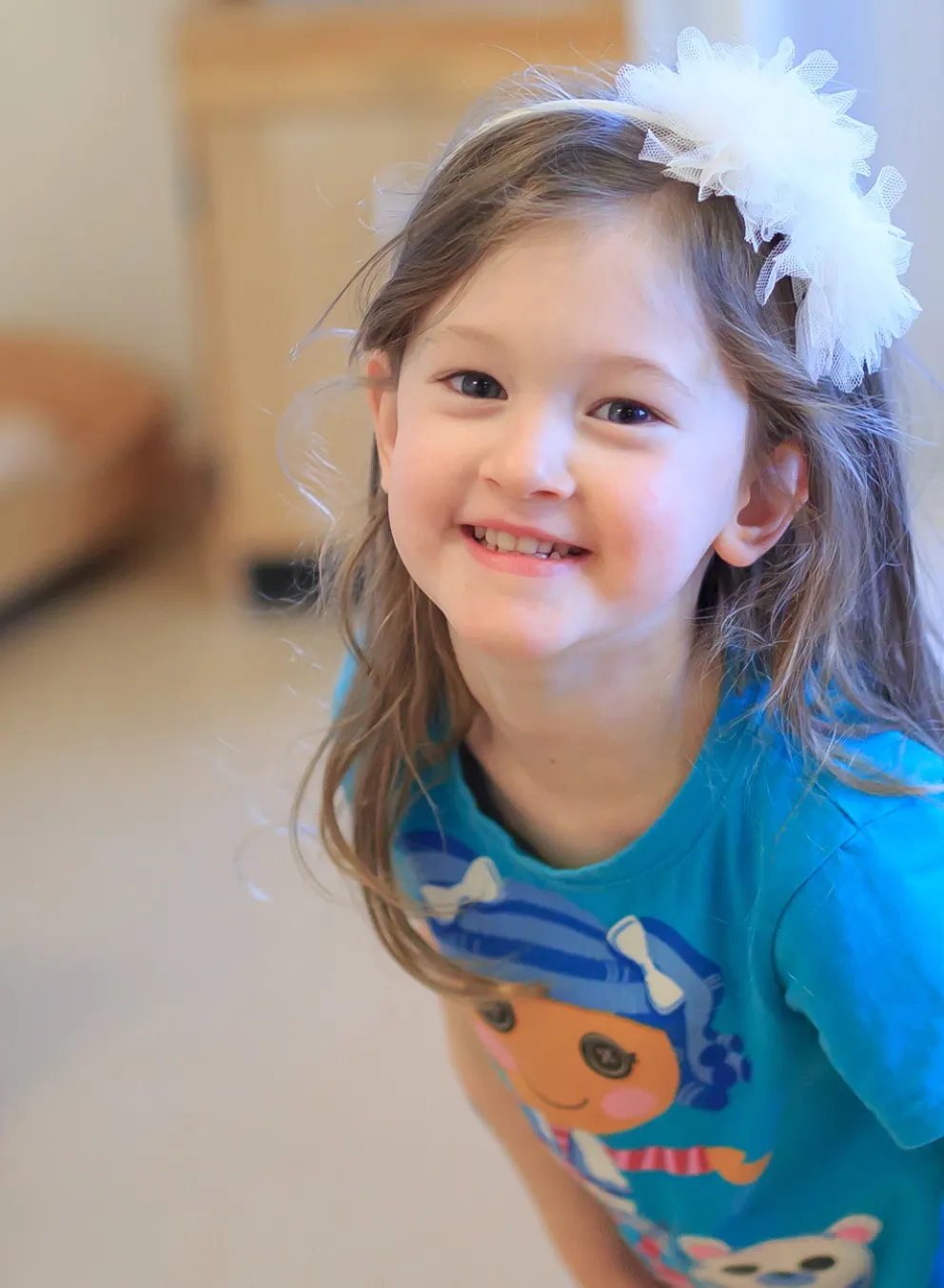 A smiling girl with a bow in her hair.