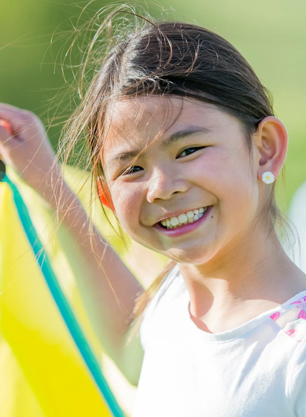 A girl holding up a section of a parachute participates in outdoor camp activities.