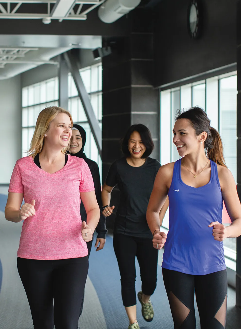 A group of friends walk together on an indoor track.