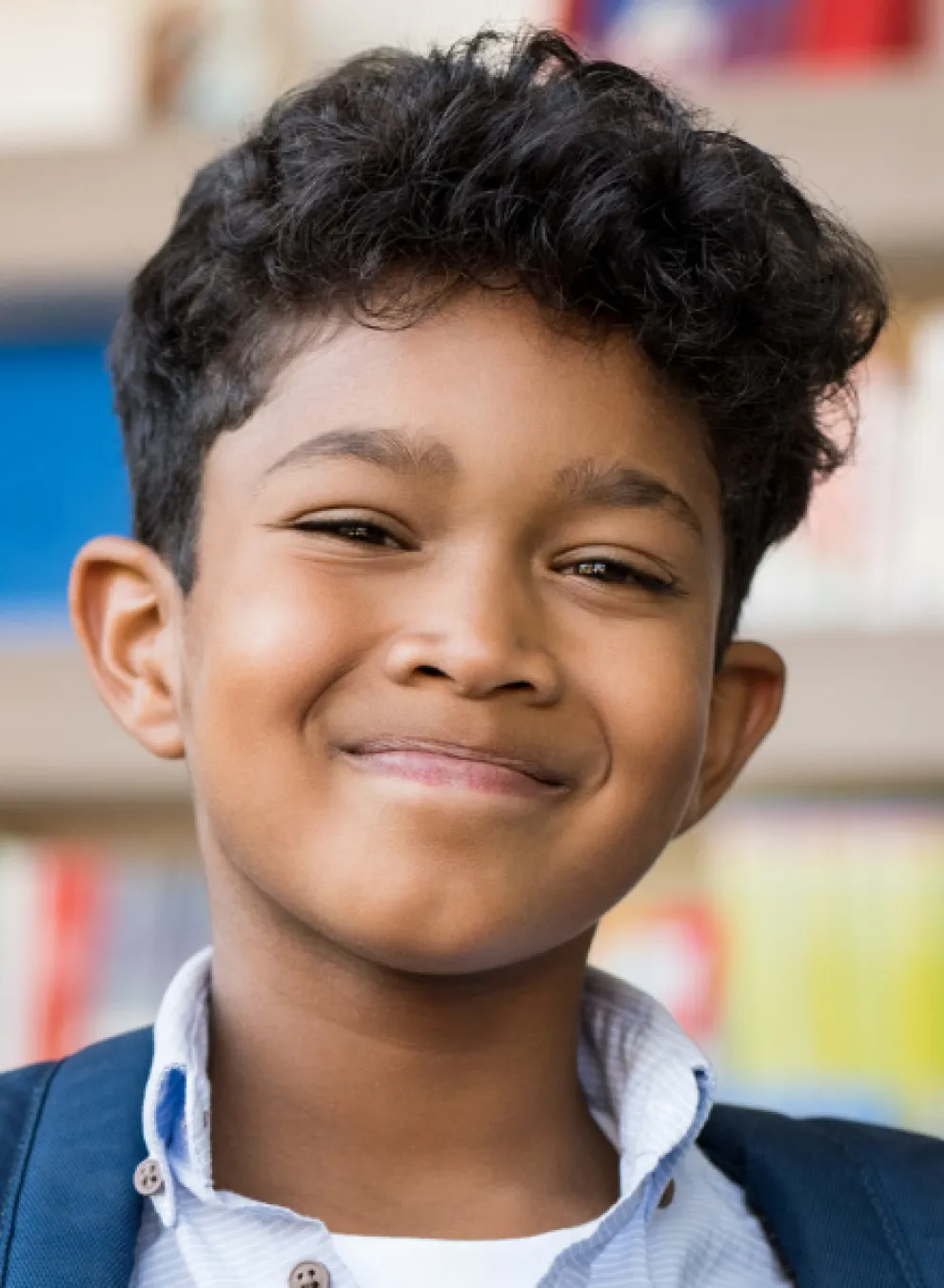 A young boy smiles in a library.