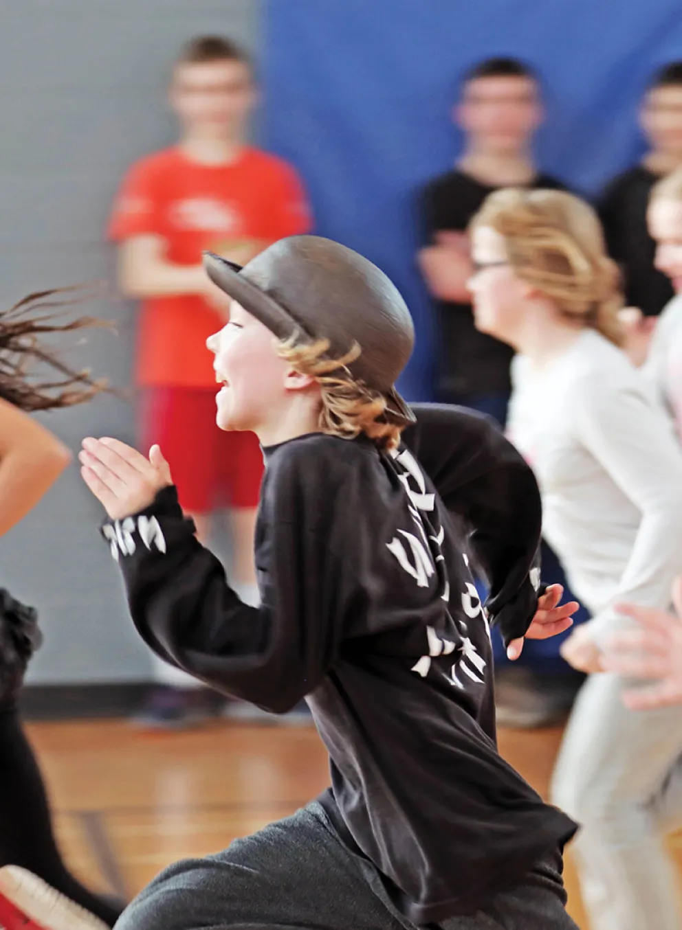 A group of children run in a gymnasium.