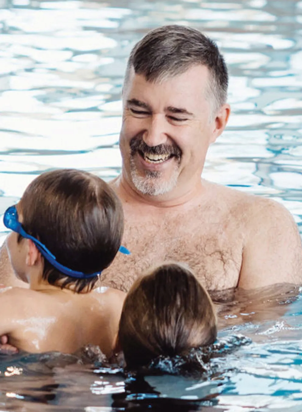 A father and his two children play in the swimming pool.