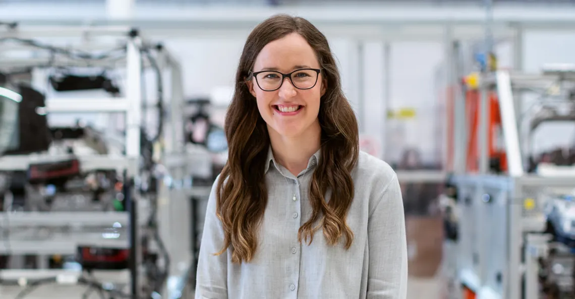 A smiling woman stands in a factory.