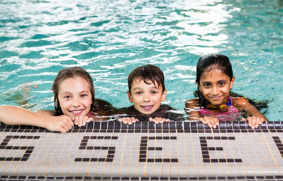 Three children at the edge of a swimming pool