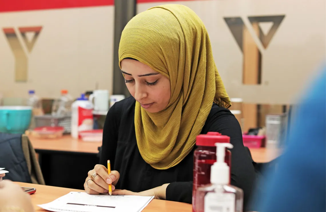 Woman sits at a classroom desk working.