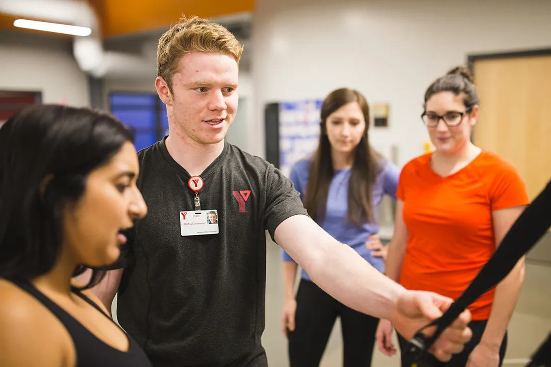 A personal trainer shows his clients how to use a piece of fitness equipment.