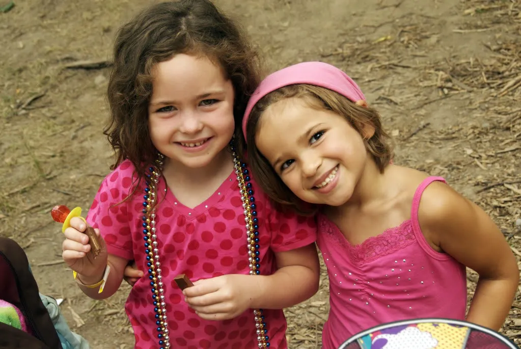 Two smiling young girls both wearing pink.