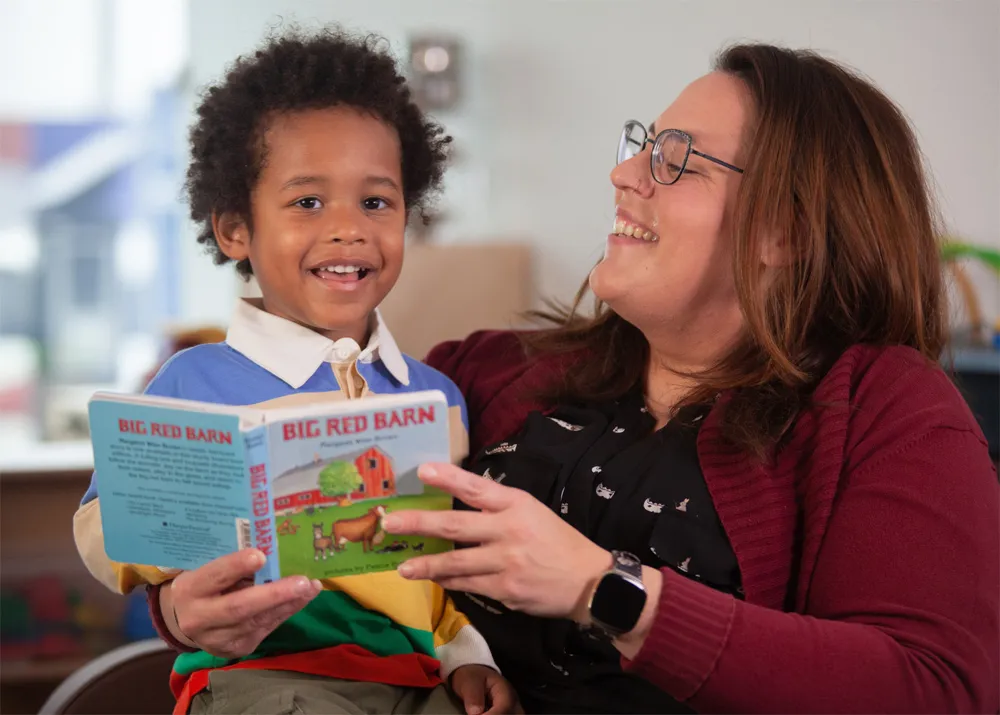 young boy and child care worker reading a book