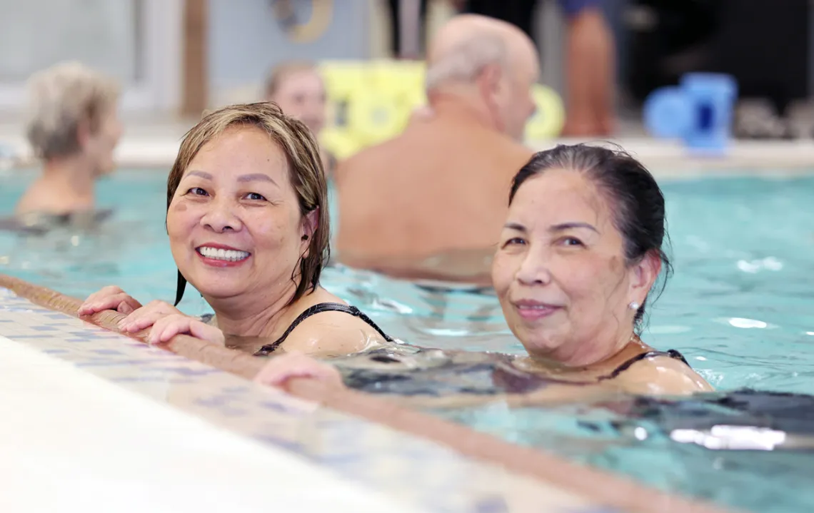 Two senior women swim in the pool.